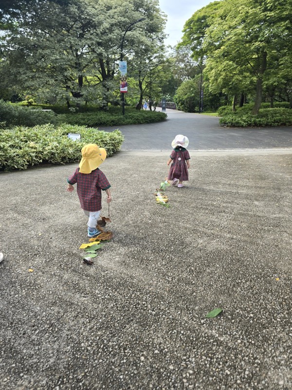 Two Pre-Nursery children exploring a trail of leaves outdoors
