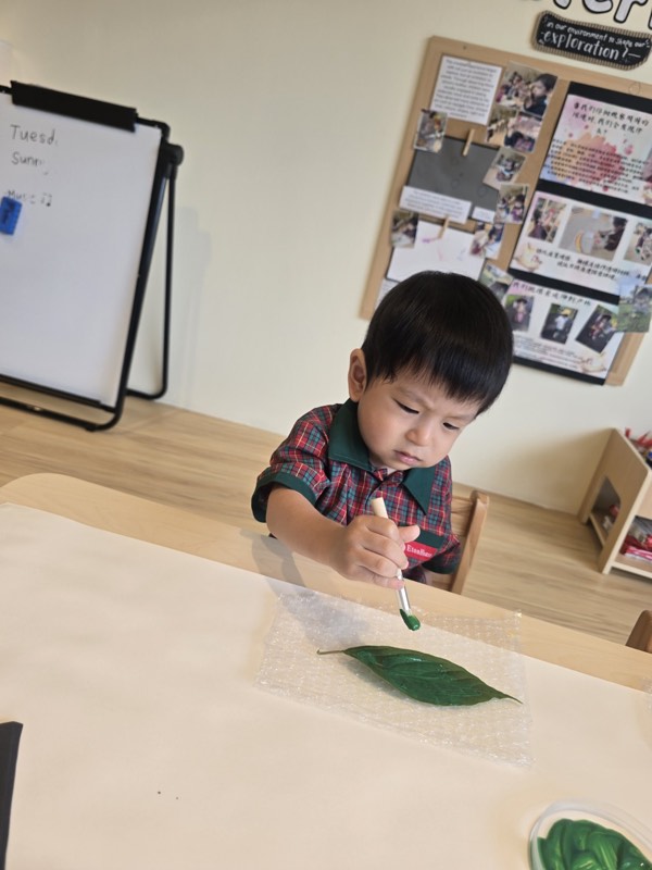 A Pre-Nursery child painting a leaf green