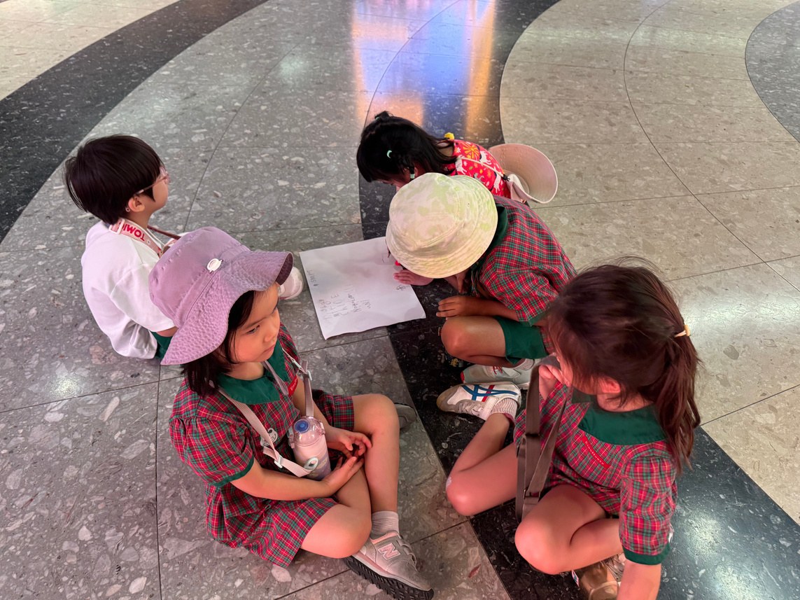 Children discussing a map during their visit to Bayfront MRT station