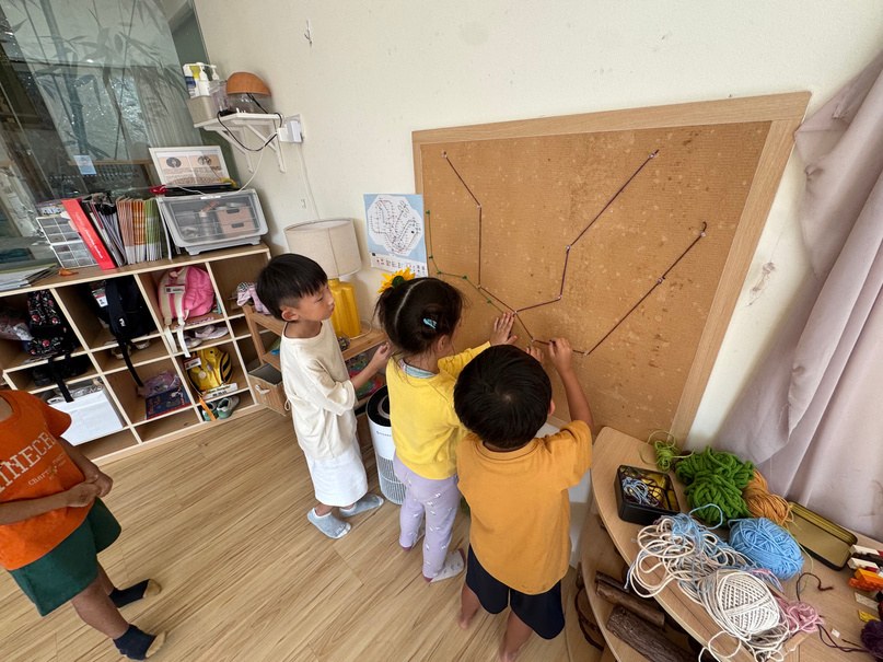 Children pinning coloured strings onto a corkboard