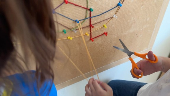 A close-up of coloured strings forming train lines
