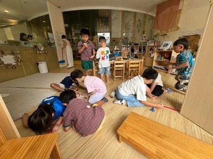 Children repositioning furniture to create a classroom train station